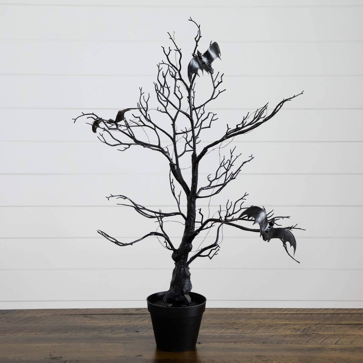 a black tree with bats in a pot