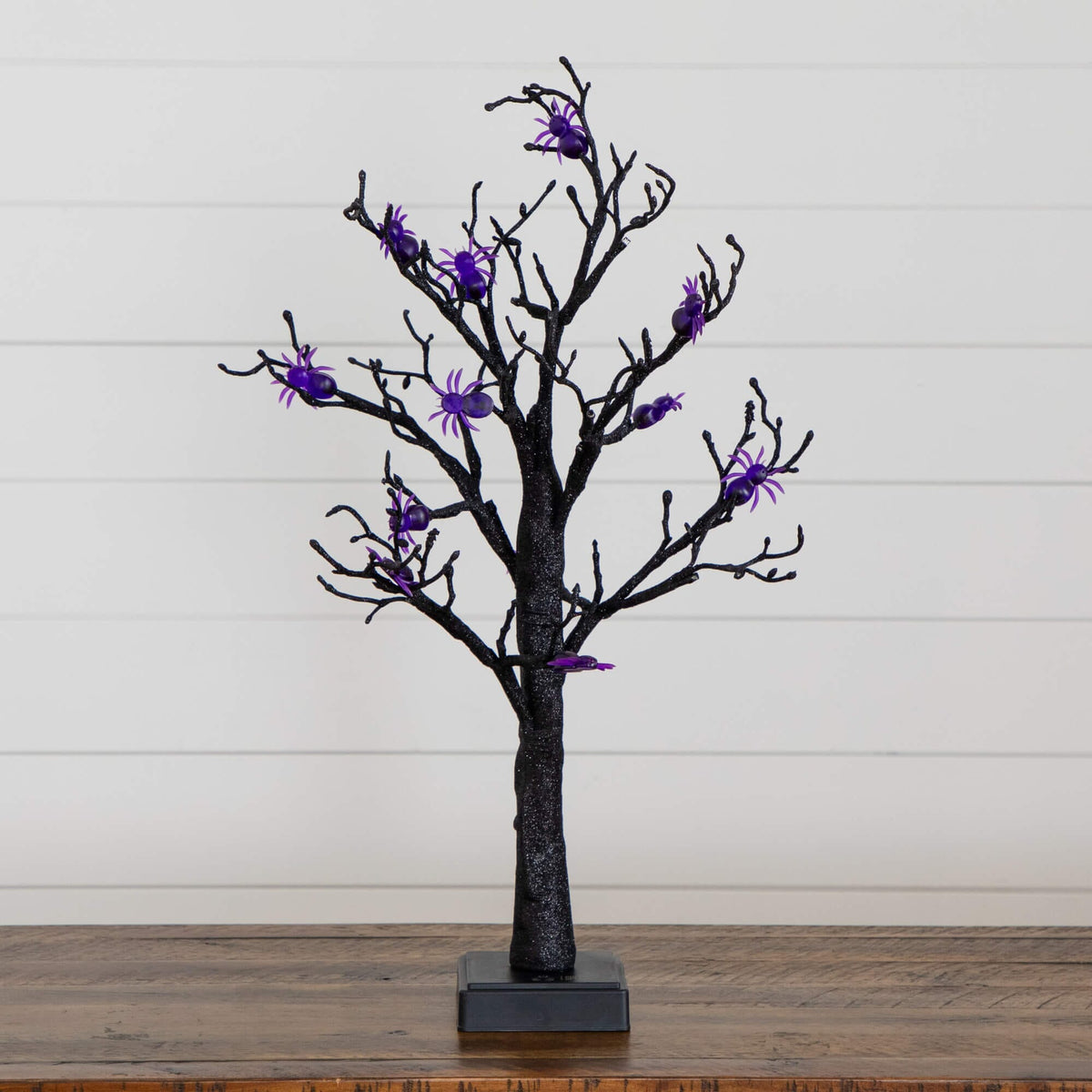 a black tree with purple spiders on it