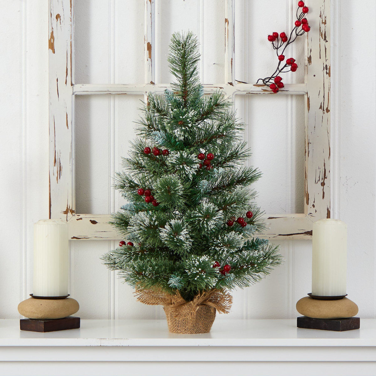 a small christmas tree with red berries and candles on a shelf