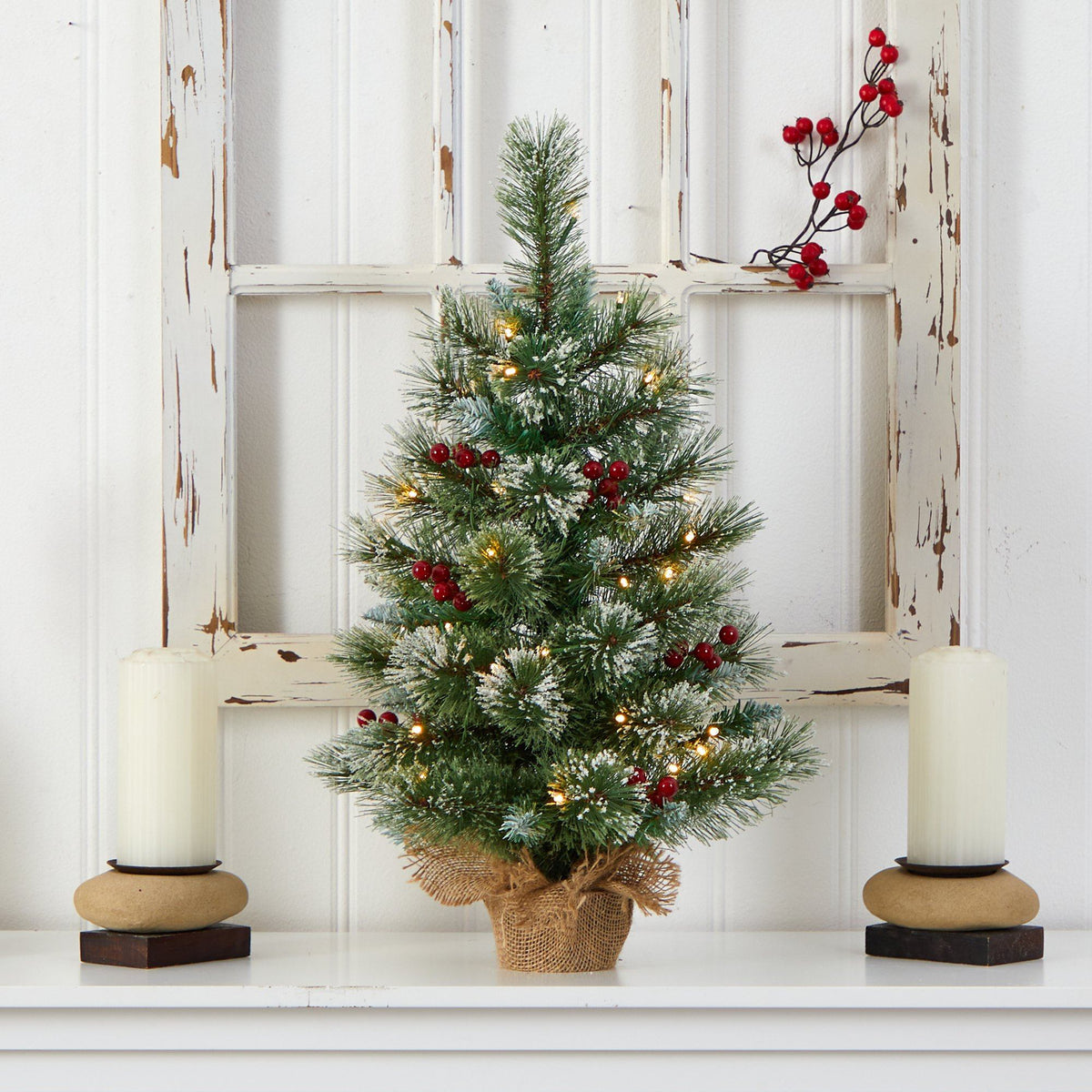 a small christmas tree with lights and candles on a shelf
