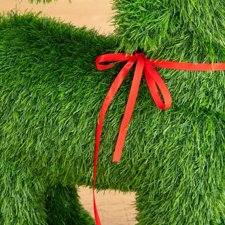 a grass dog with a red ribbon