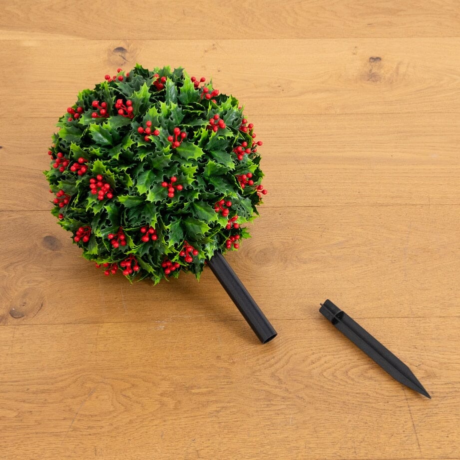 a tree with red berries and a pencil on a wood surface