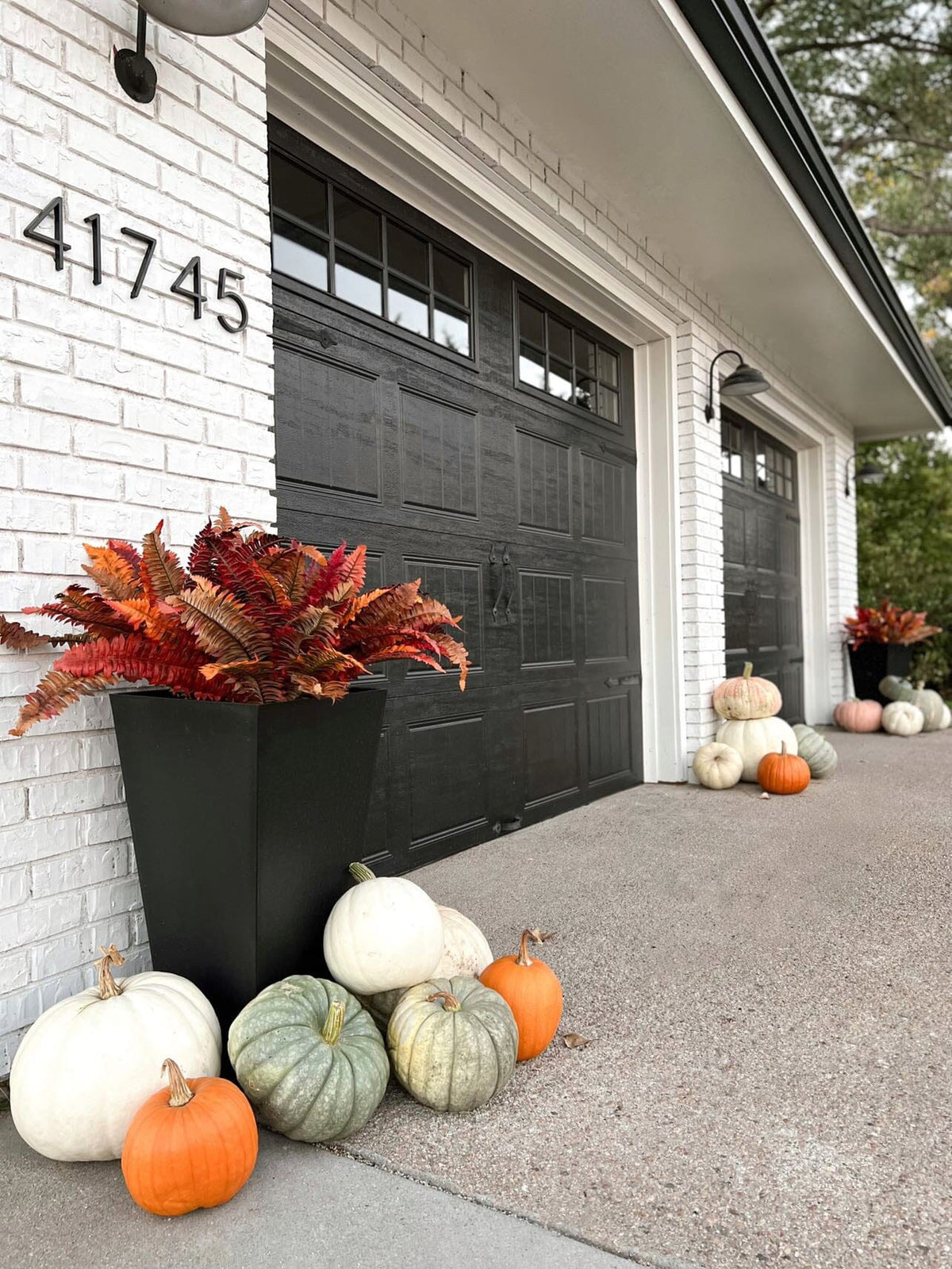 pumpkins and pumpkins on a sidewalk next to a garage