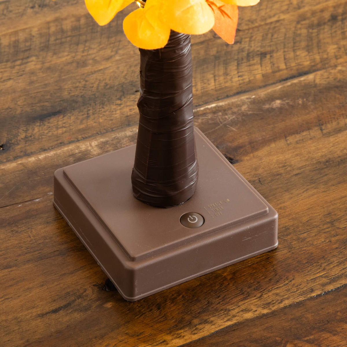 a plastic flower vase on a brown square base