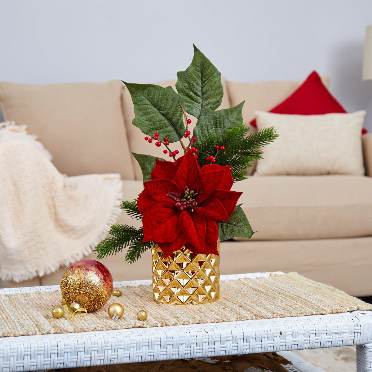 a red and green poinsettia in a gold vase on a white coffee table