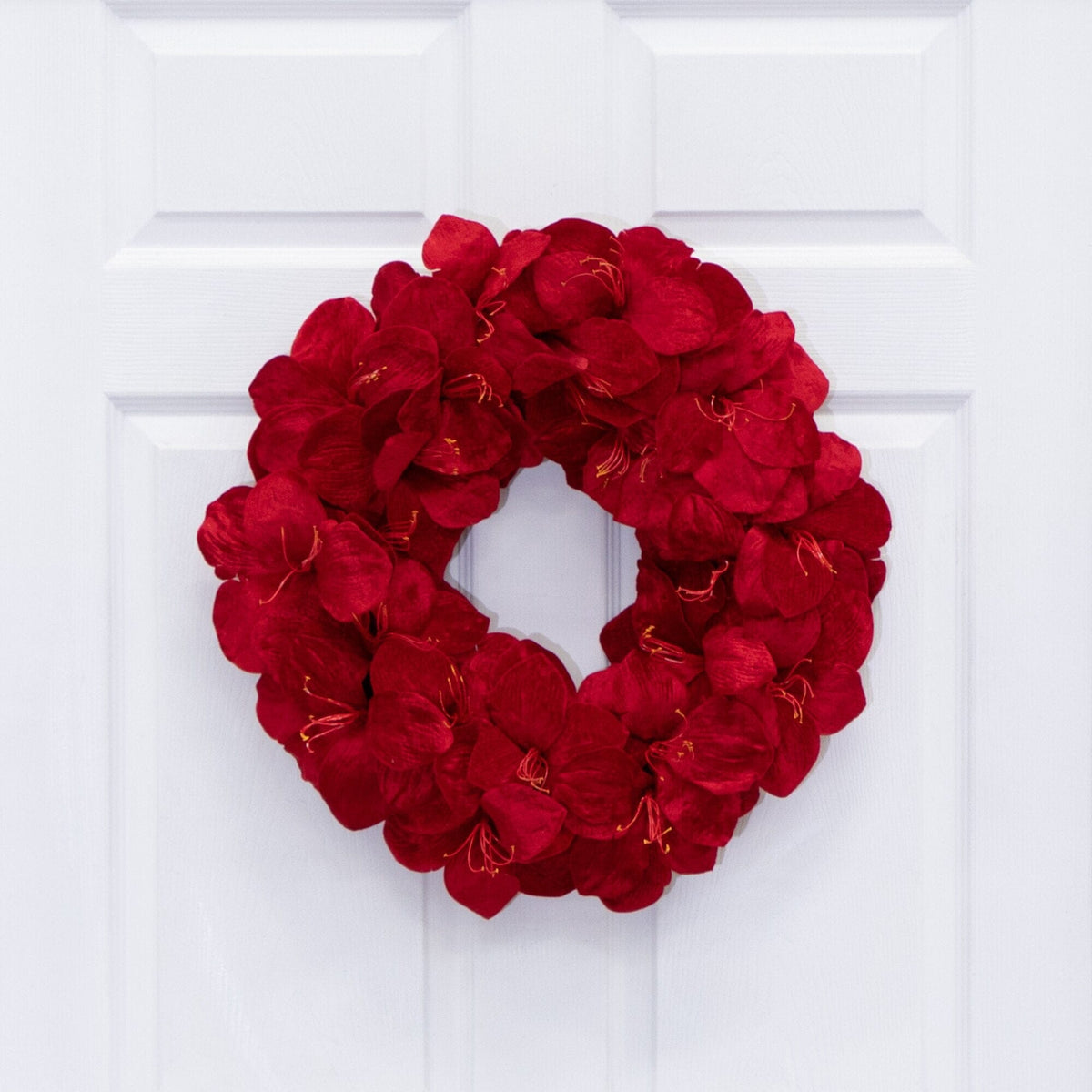 a red flower wreath on a white door