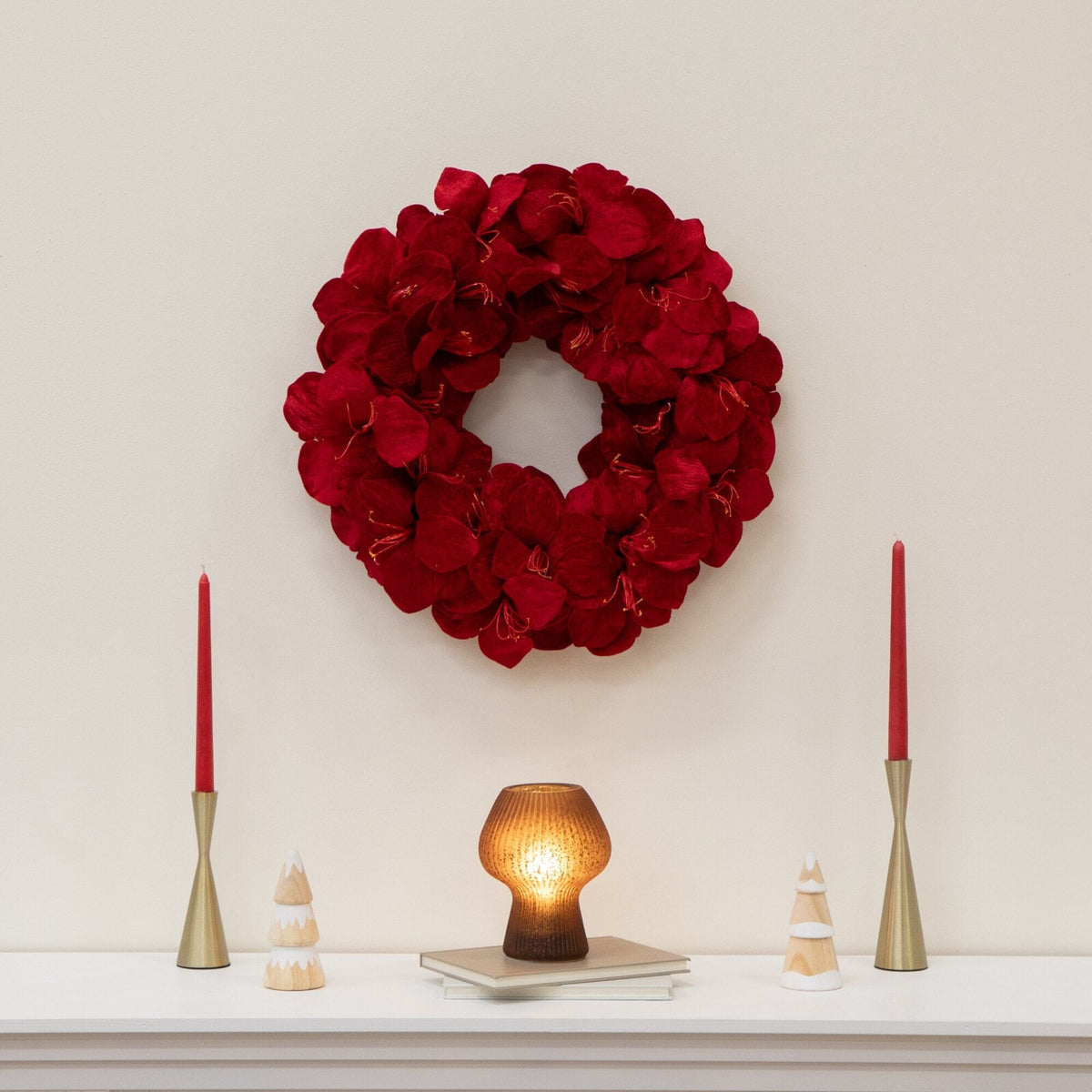a wreath and candles on a white shelf