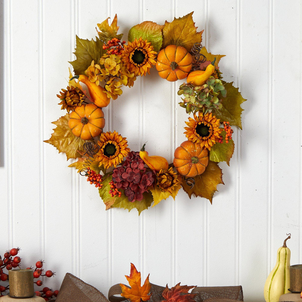 a wreath with pumpkins and flowers on a white wall