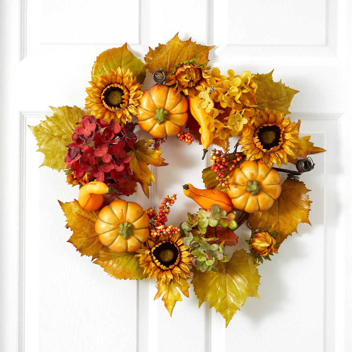 a wreath with pumpkins and flowers on a white door
