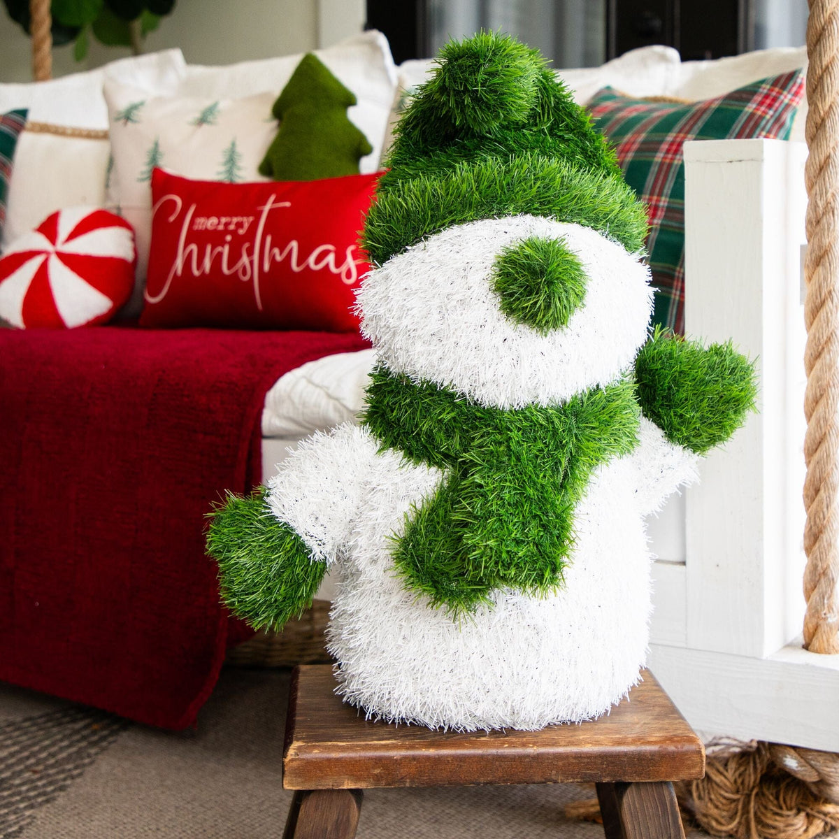 a green and white snowman on a wooden stool