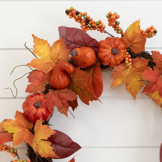 a wreath with orange leaves and pumpkins