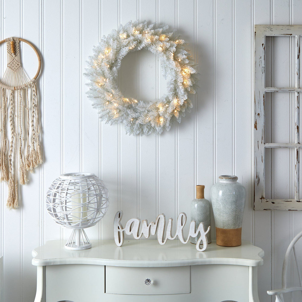 a white table with a wreath and a dream catcher on the wall