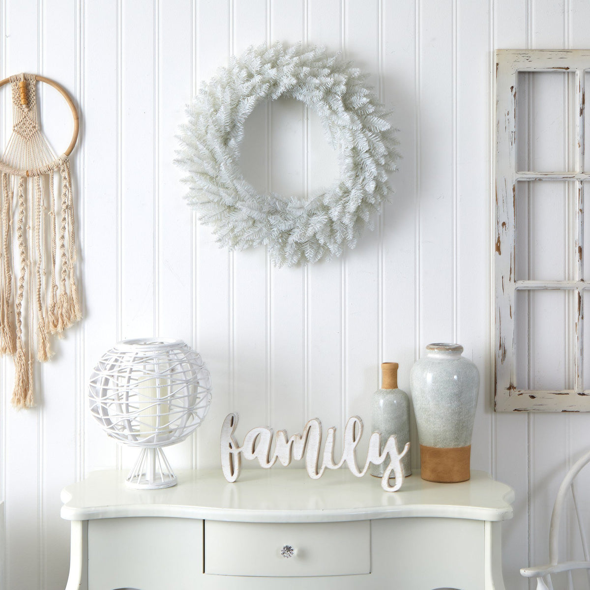 a white table with a wreath and a dream catcher on the wall