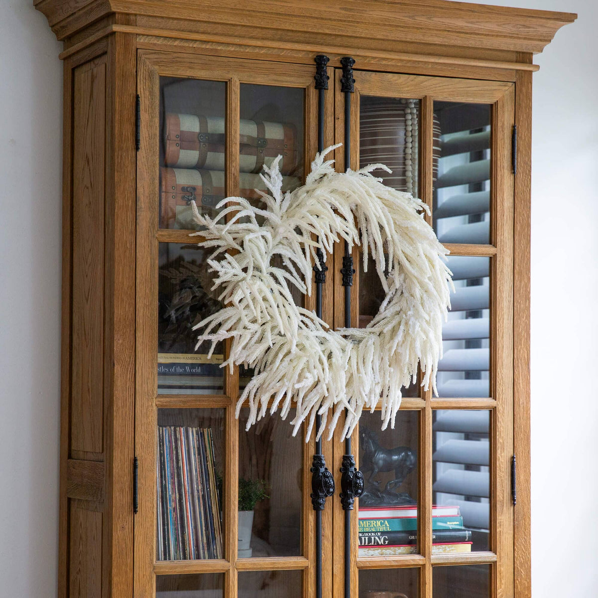 a white wreath on a glass cabinet