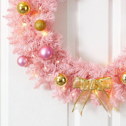 a pink wreath with lights and ornaments