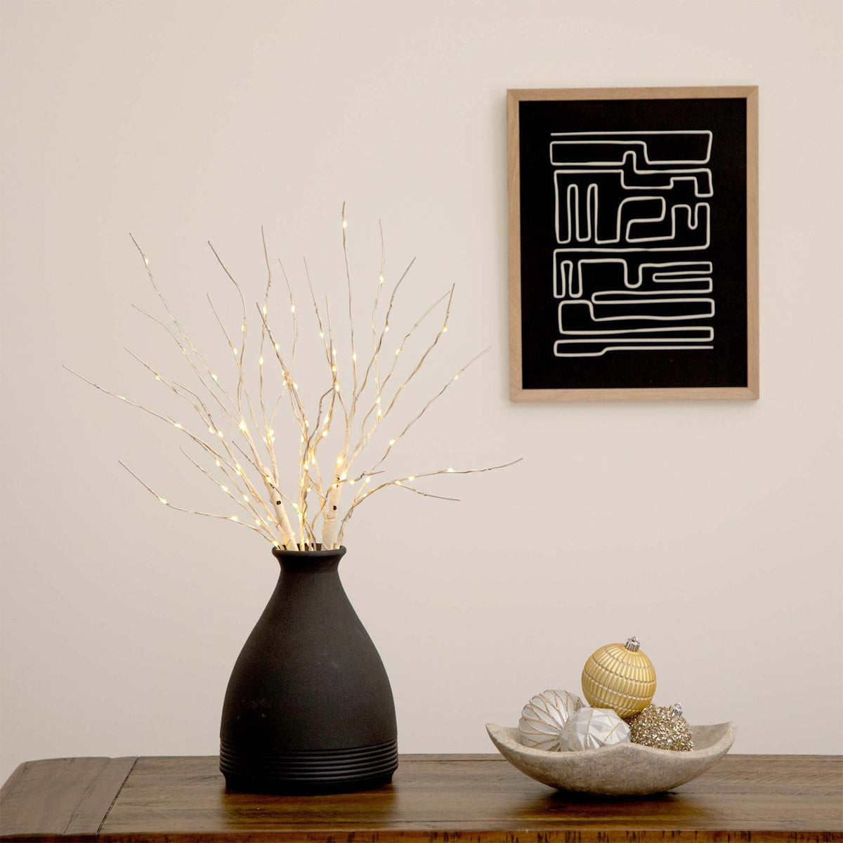 a vase with lights in it and a bowl of ornaments on a table