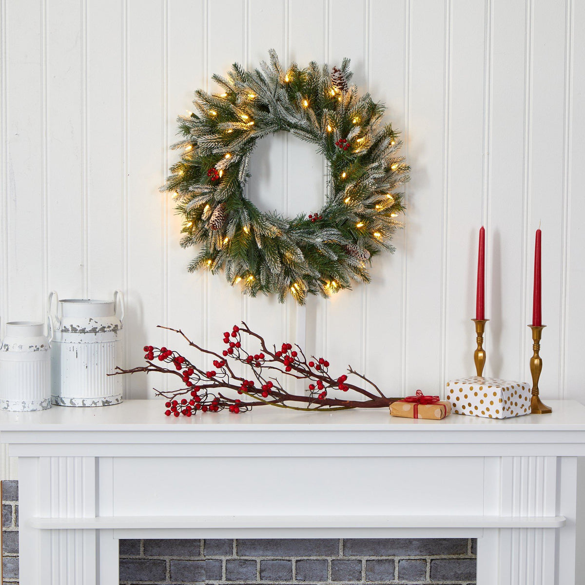 a white fireplace with a wreath and candles