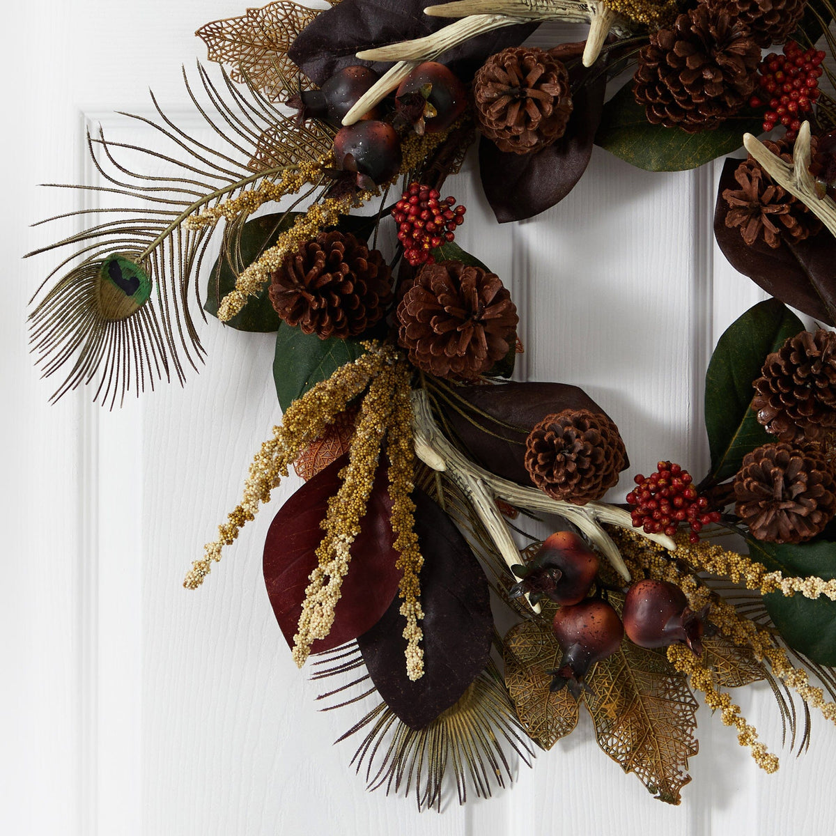 a wreath with pine cones and leaves on a white door