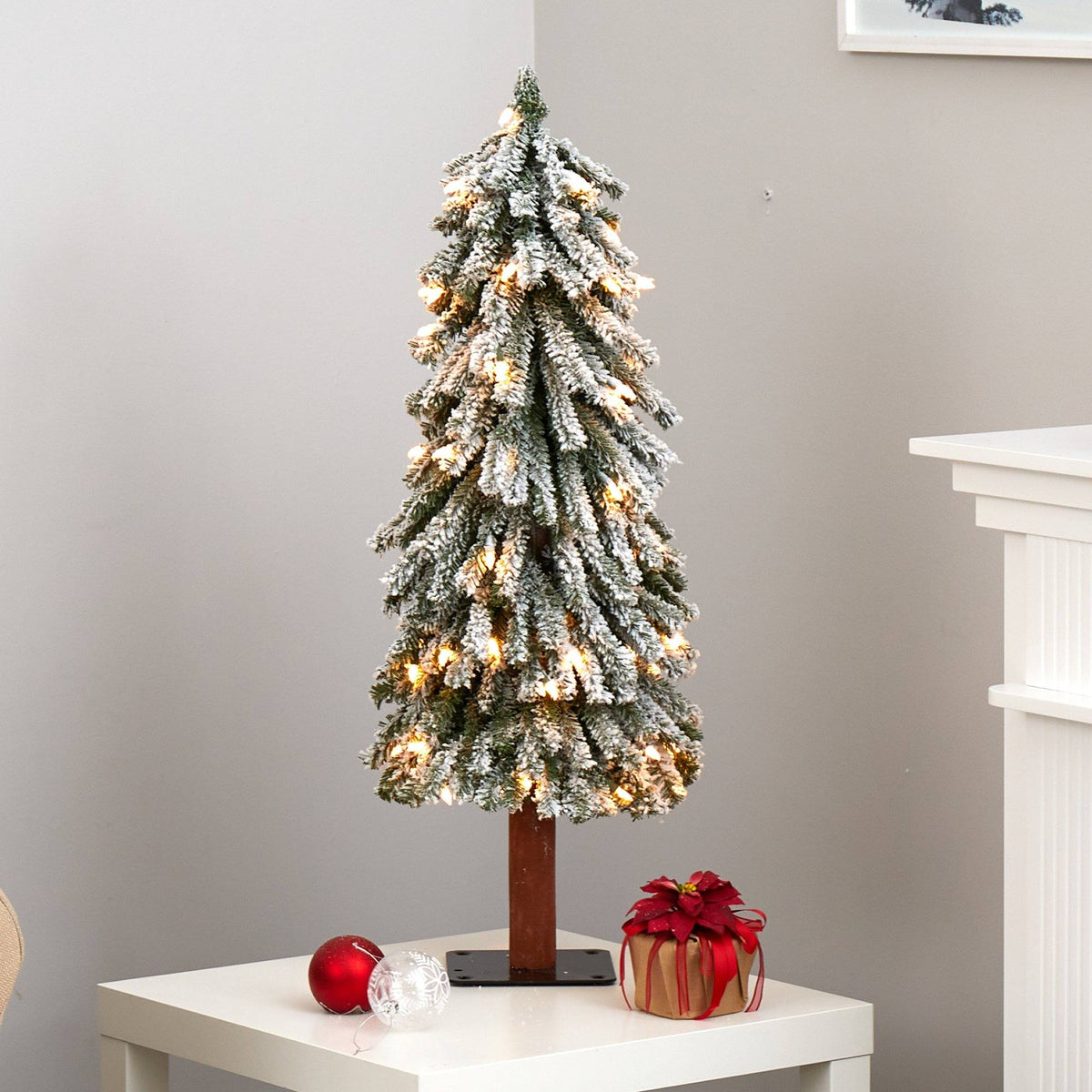 a small artificial christmas tree with lights on a white table