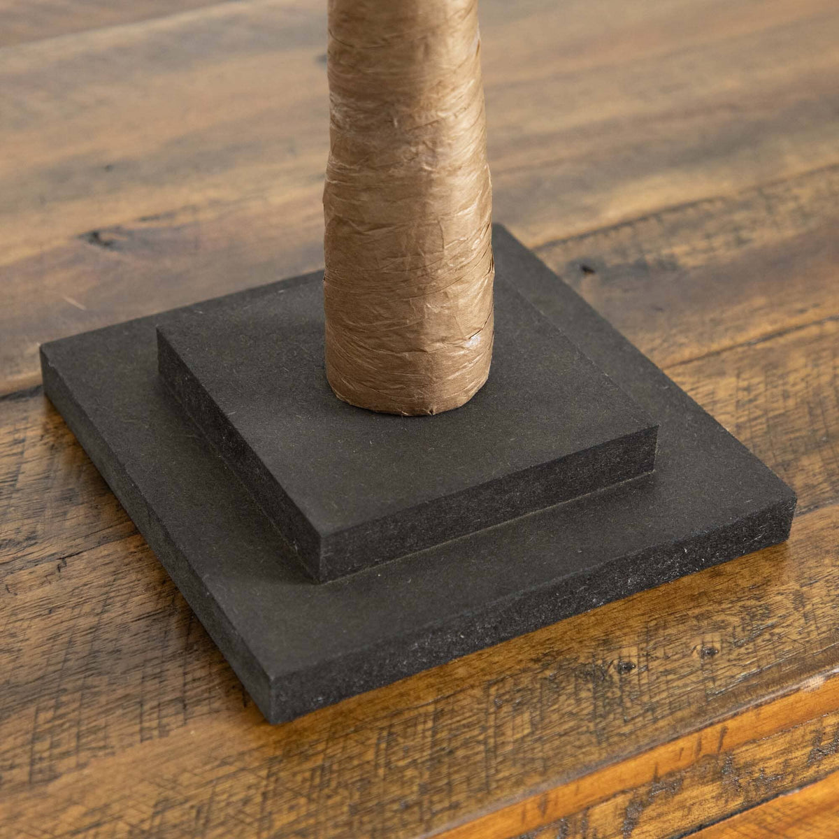 a cardboard tube on a black square platform