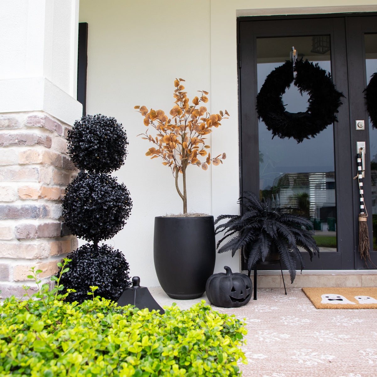 a front porch of a house with a plant and wreaths