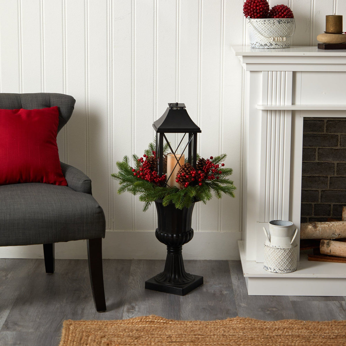 a black lantern with red berries in a vase next to a fireplace