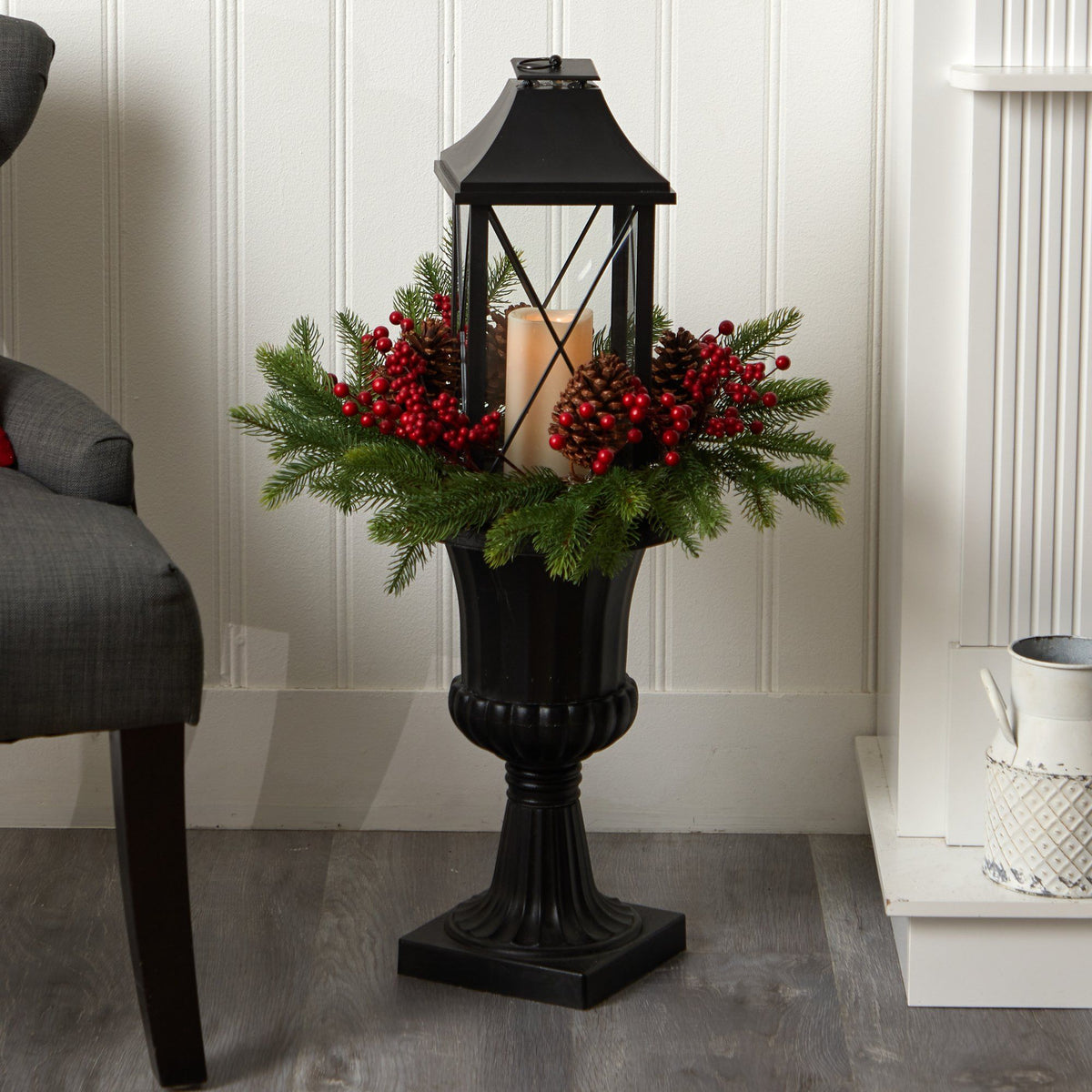 a black lantern with red berries and pine cones in a vase