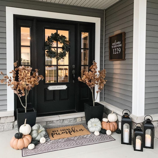 a front porch of a house with a door and pumpkins