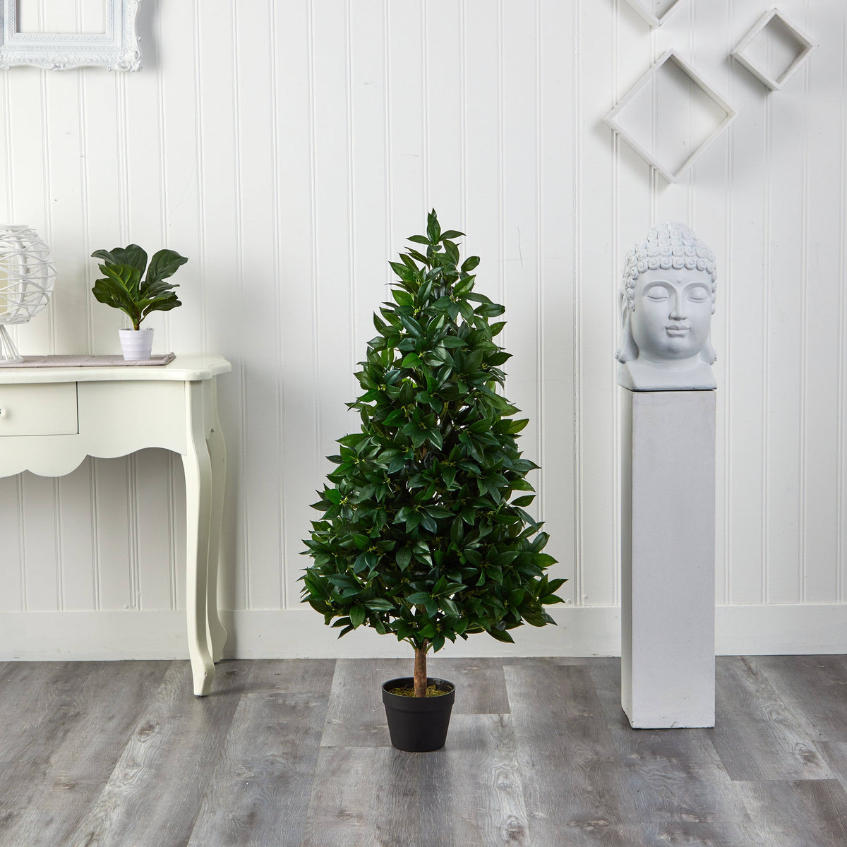 a tree in a pot next to a white table