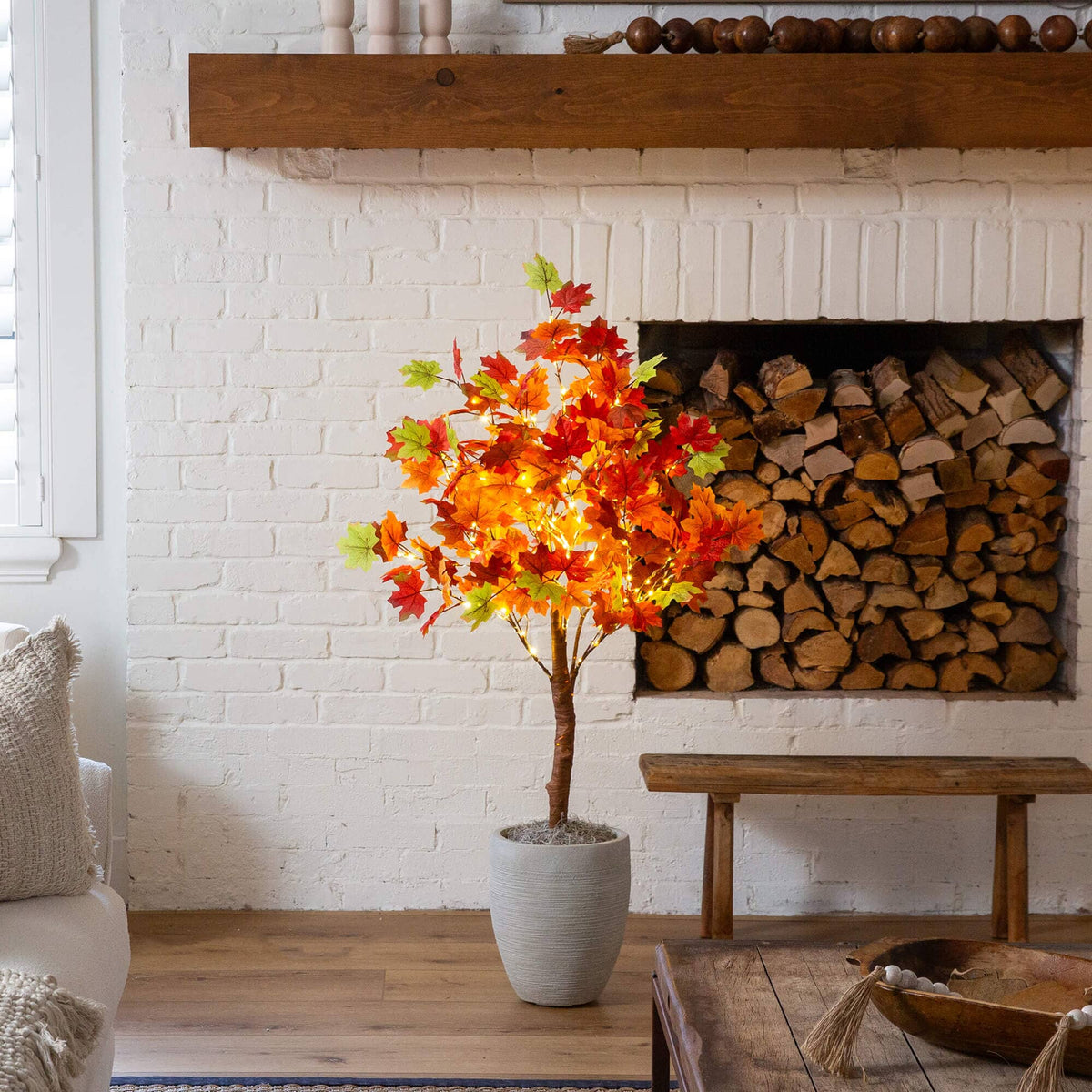 a tree in a vase in front of a fireplace