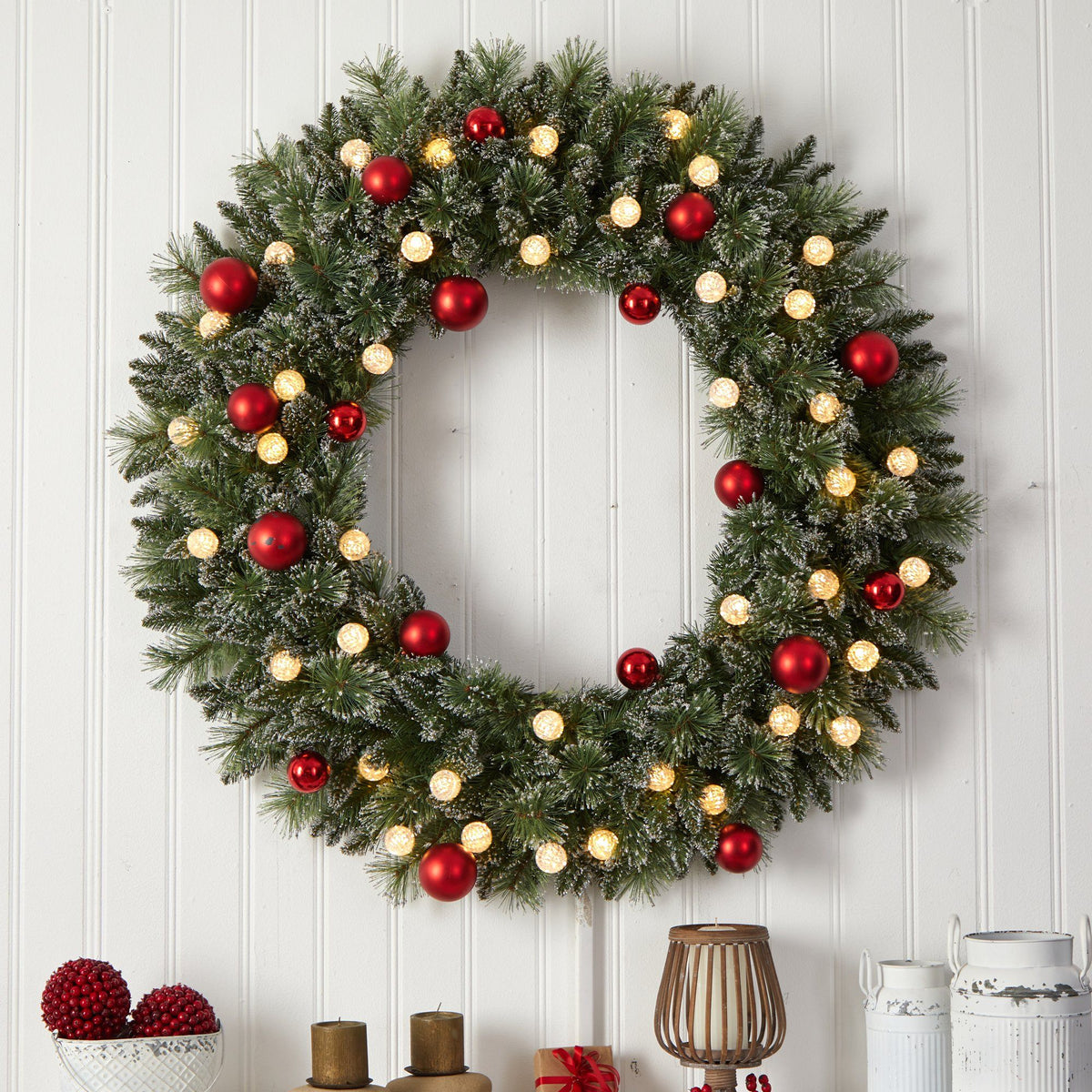 a wreath with lights and ornaments on a wall