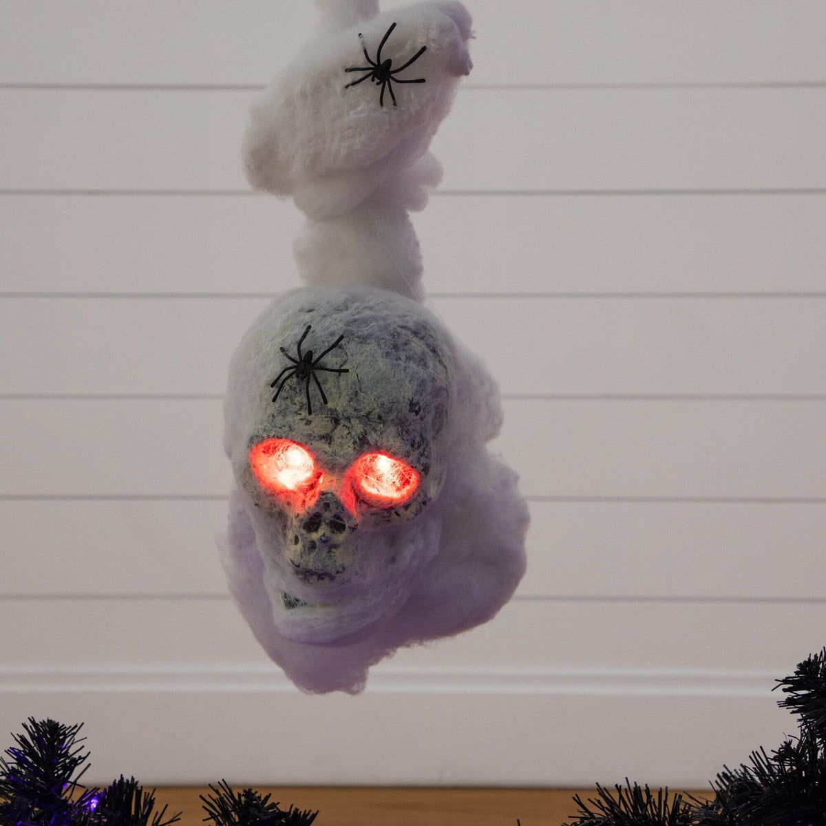 a white skull with red eyes and spiders from a tree