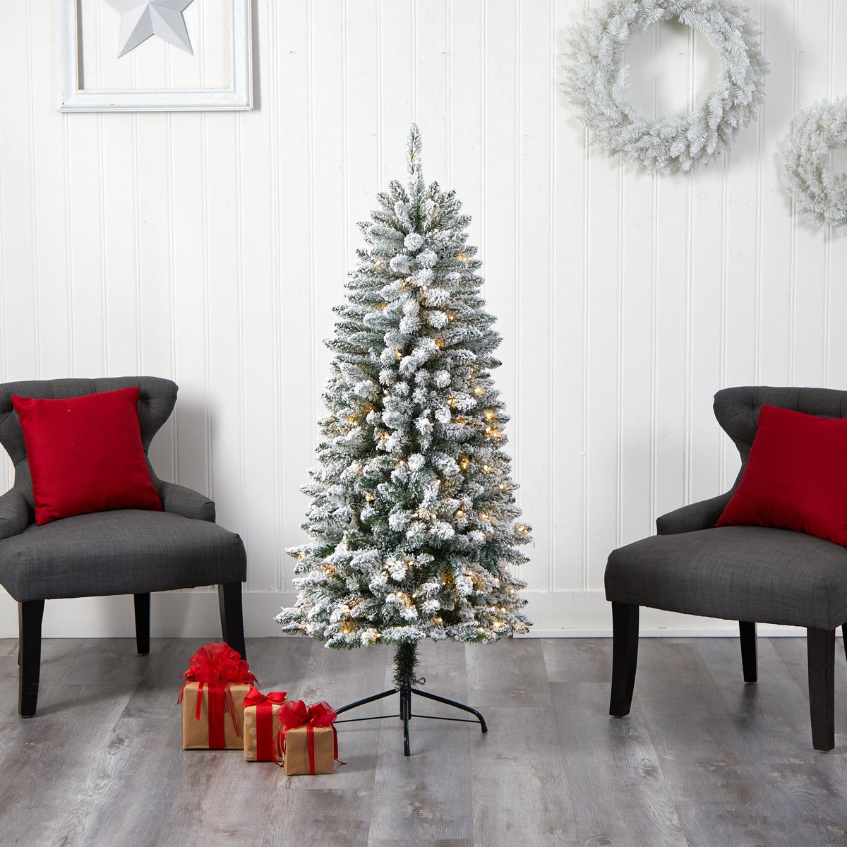 a christmas tree with lights and presents in front of a white wall