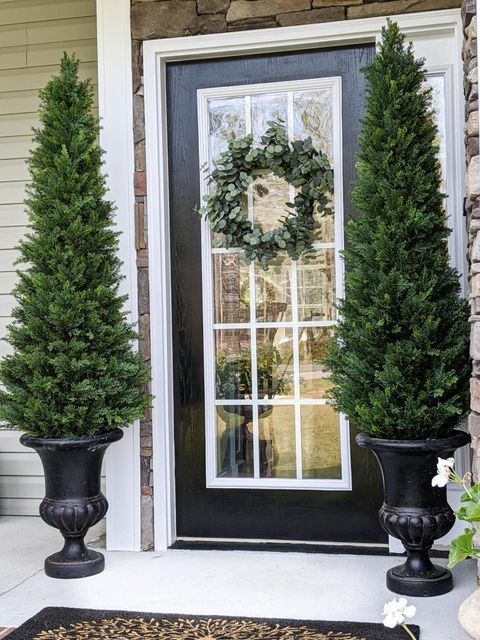 a front door with a wreath and two trees