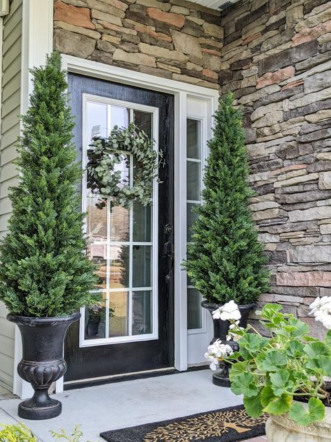 a front door of a house with a wreath and trees