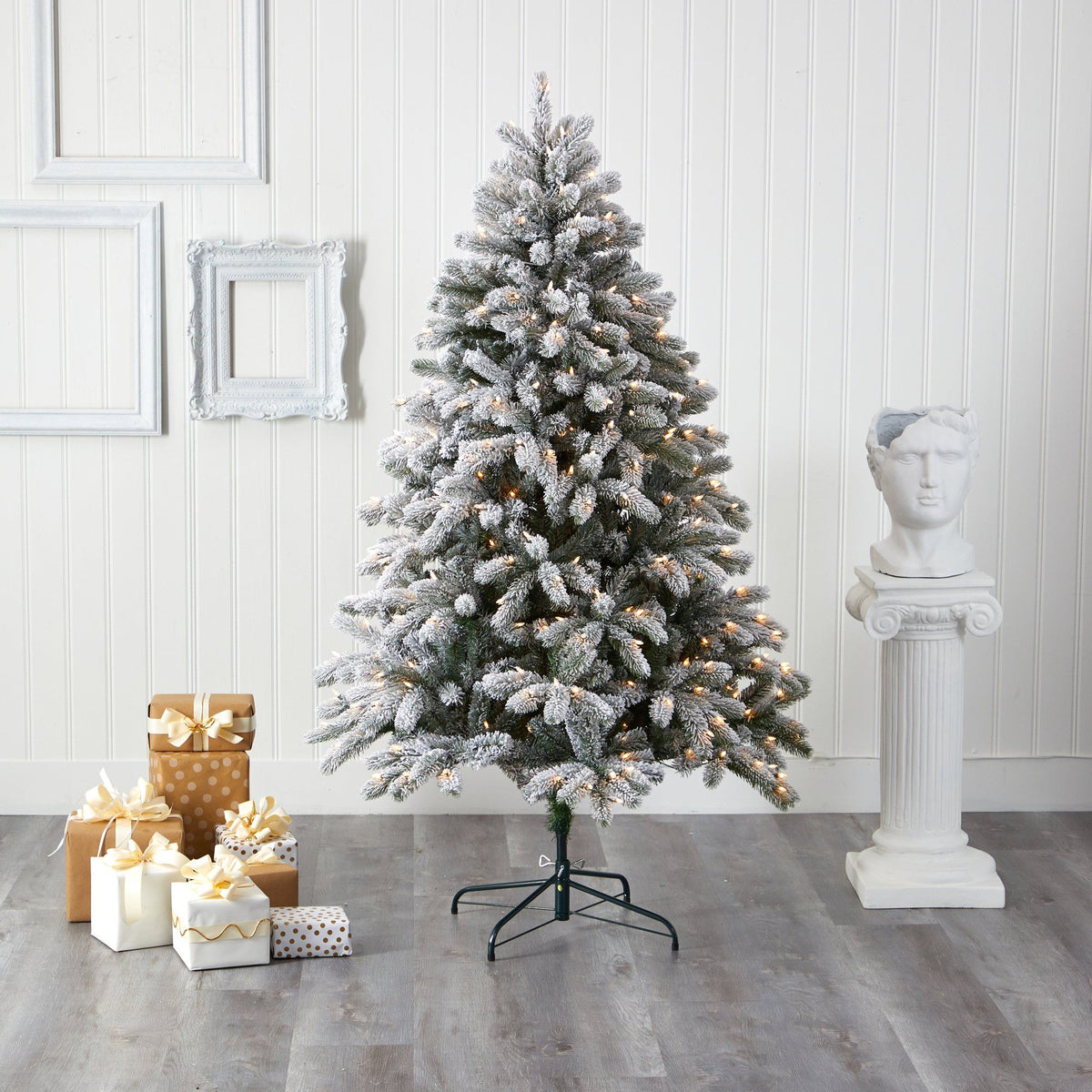 a christmas tree with presents in front of a white wall