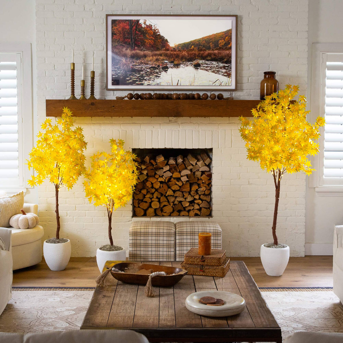 a living room with a fireplace and yellow trees
