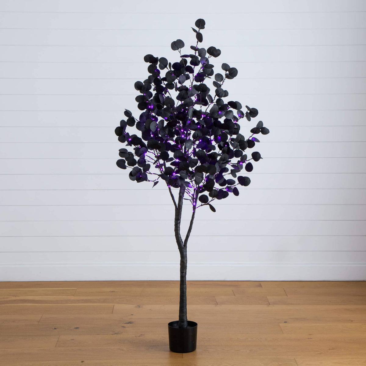 a tree with purple lights in a pot