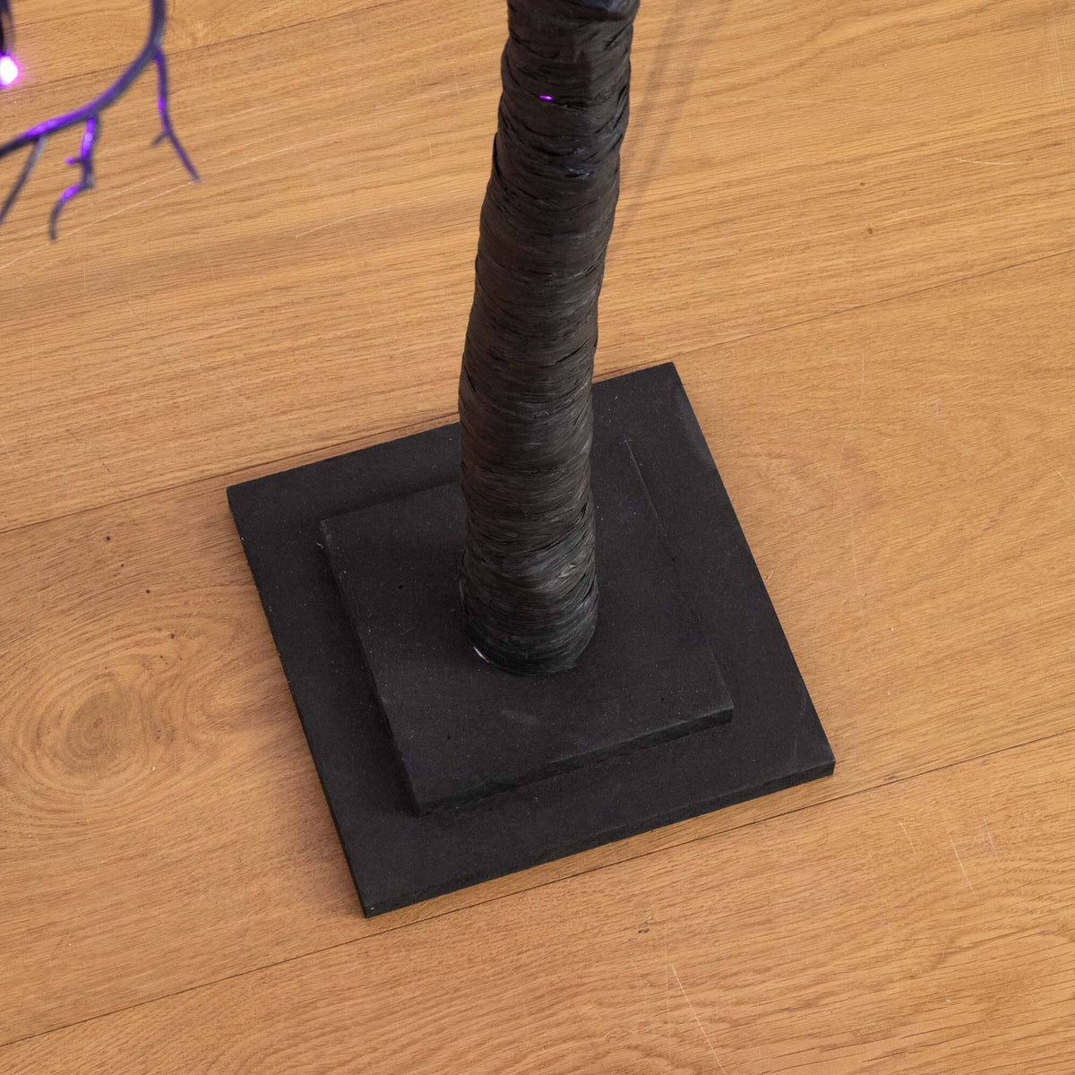 a black tree on a wood floor
