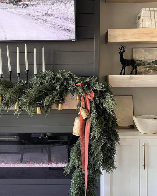 a garland of greenery and candles on a fireplace
