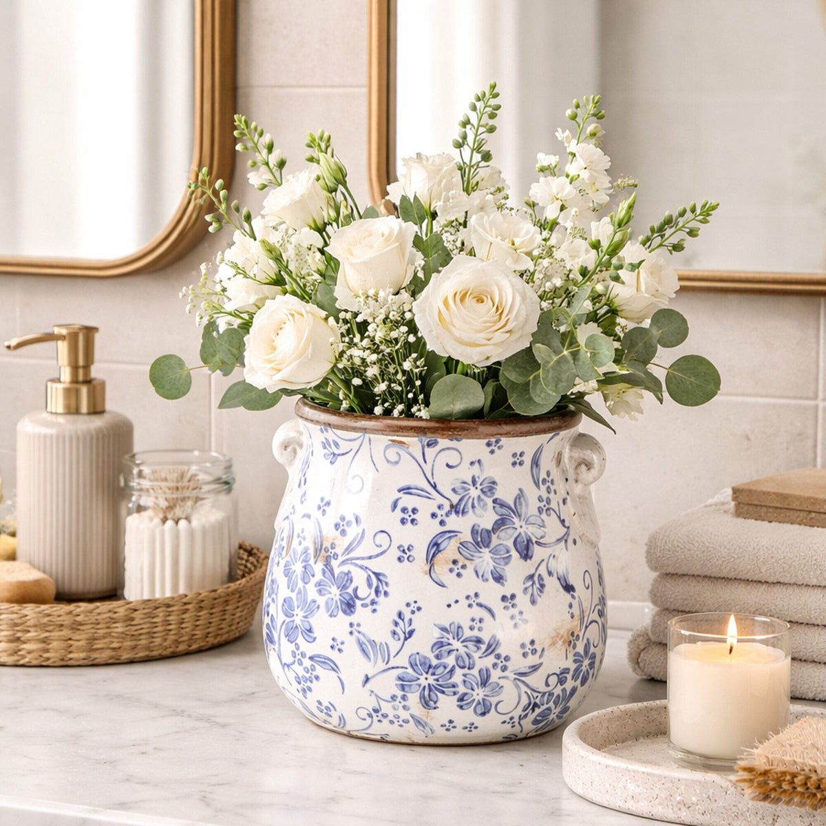 a vase with flowers and candles on a counter