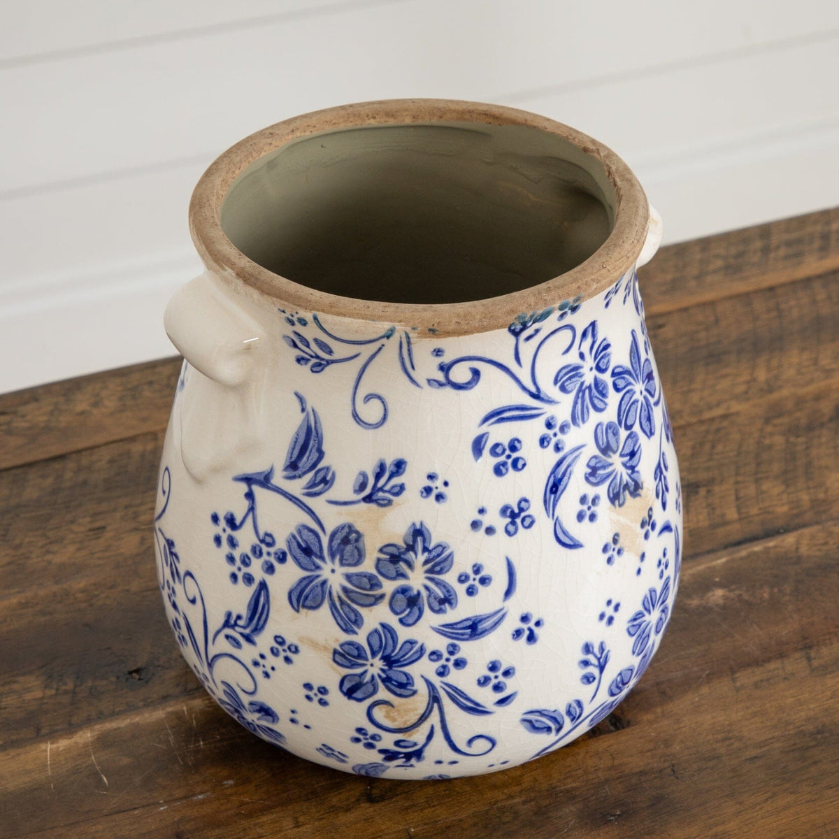 a blue and white vase on a wood surface