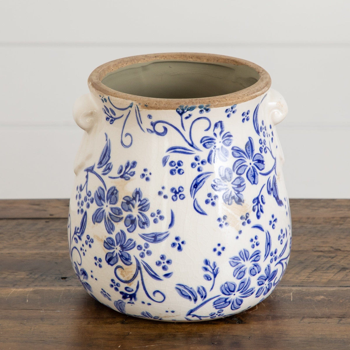 a blue and white vase with flowers on a wood surface