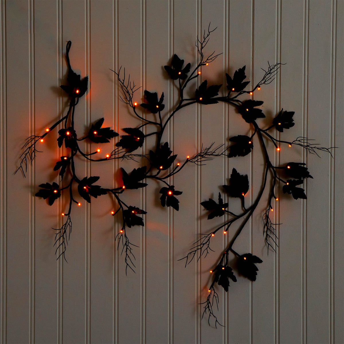 a black vine with orange lights on a white wall