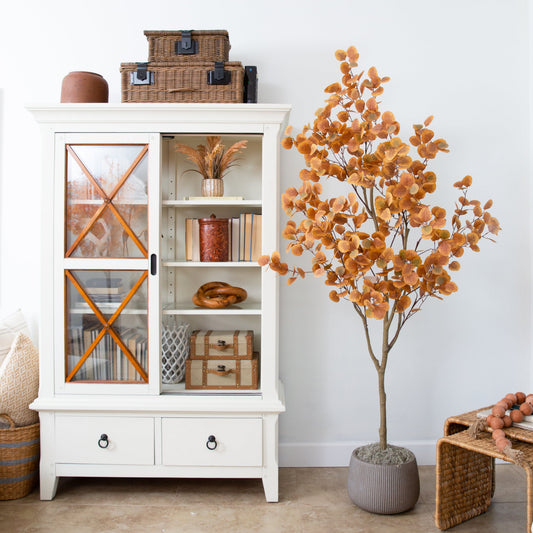 a white cabinet with a tree in front of it