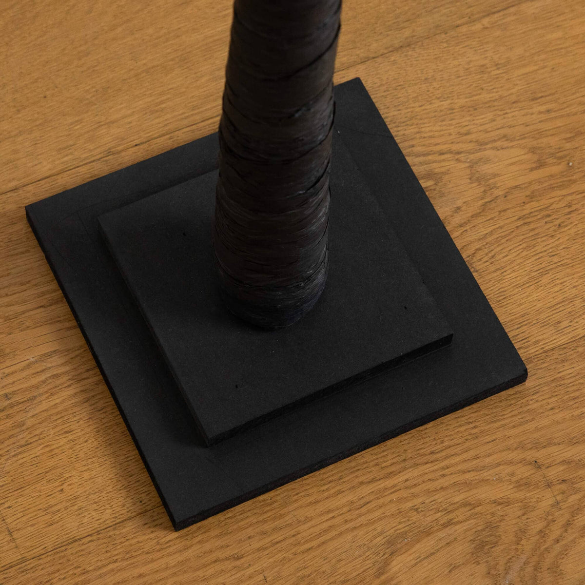 a black rope wrapped around a black square on a wood surface