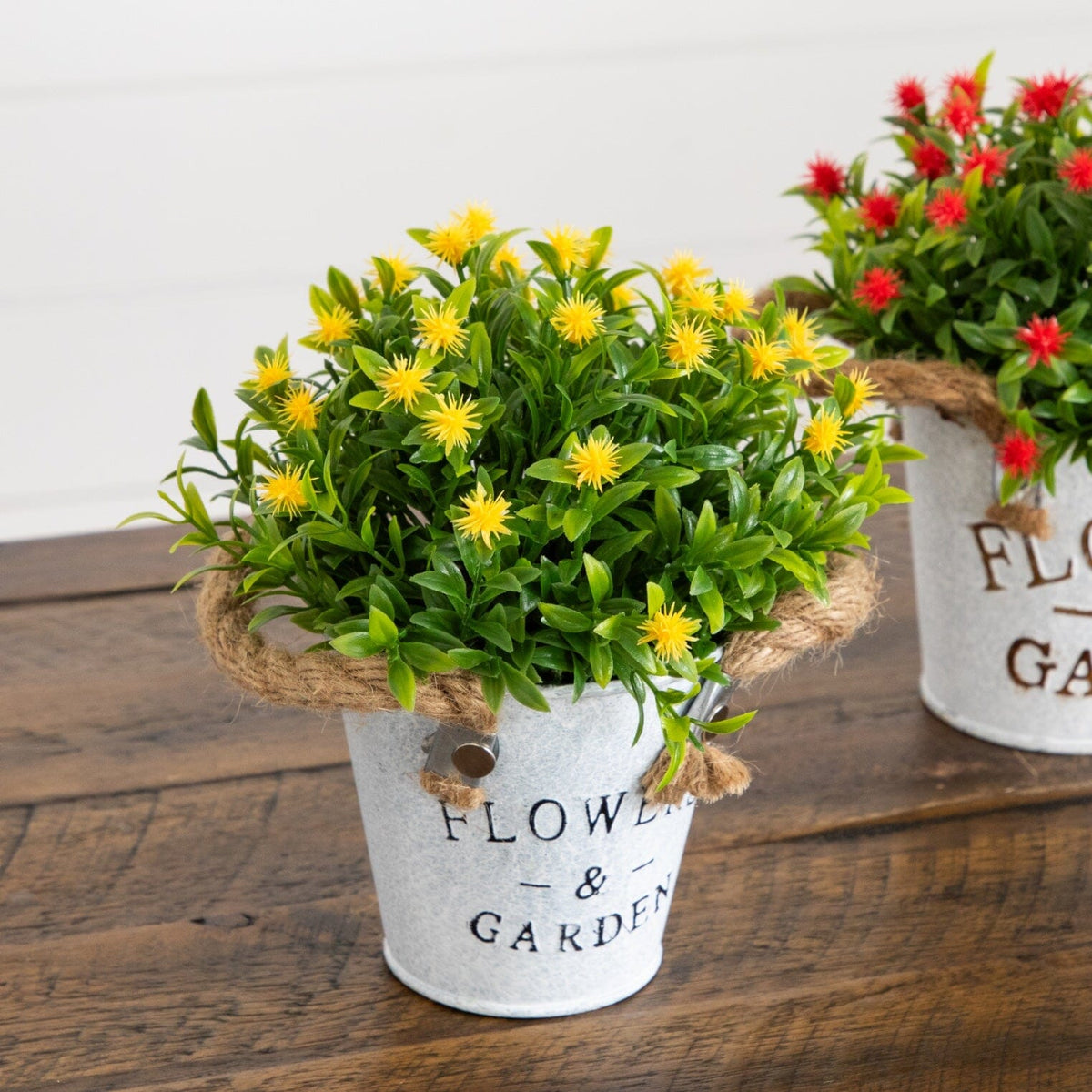 two small white buckets with yellow and red flowers