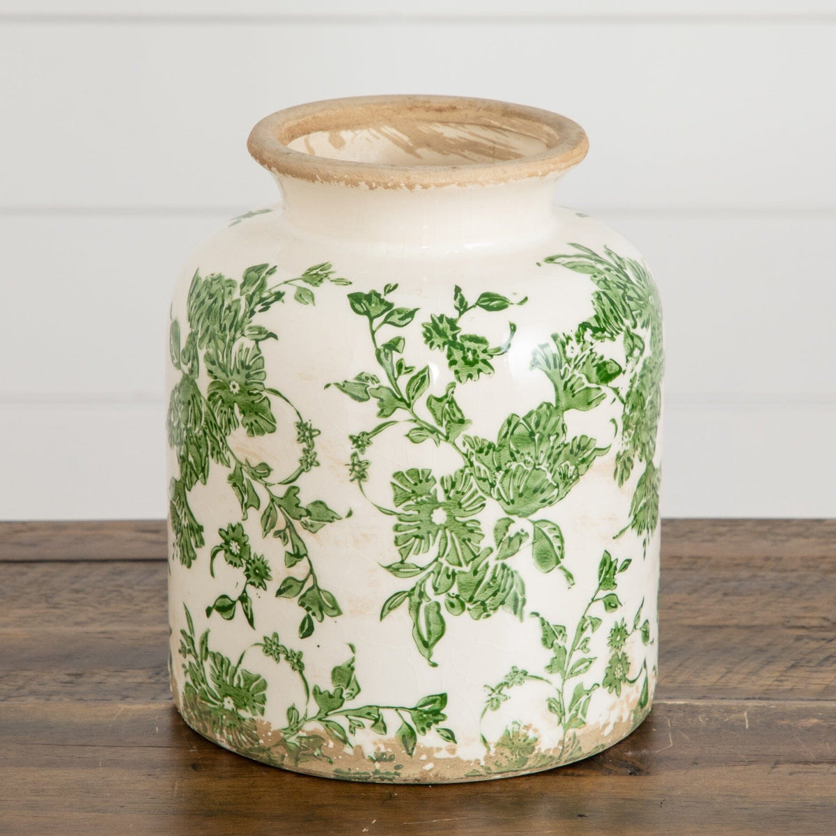 a vase with green and white floral designs