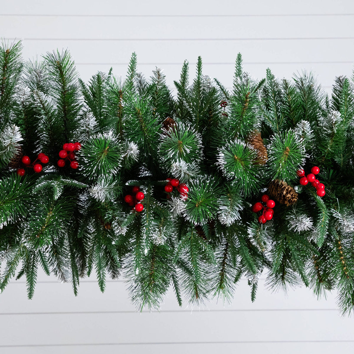 a green garland with red berries and pine cones