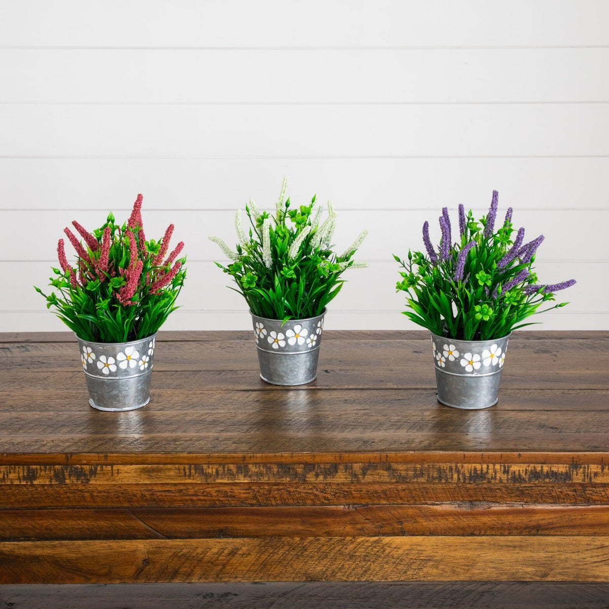 a group of artificial plants in buckets on a wooden surface